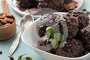 Chocolate ice cream with liquid chocolate and with a cinnamon stick, coffee beans and almonds on a blue wooden background