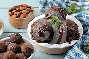 Chocolate ice cream with liquid chocolate and with a cinnamon stick, coffee beans and almonds on a blue wooden background