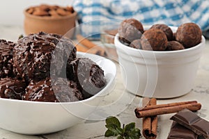 Chocolate ice cream with liquid chocolate and cinnamon sticks on a light concrete background