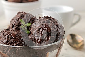 Chocolate ice cream with liquid chocolate and cinnamon sticks on a light concrete background