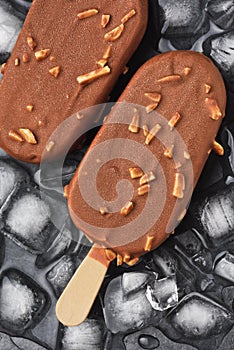 Chocolate ice cream popsicle on black background with ice