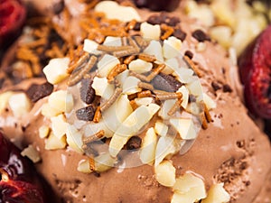 Chocolate ice cream with sprinkles, nuts and fresh cherries, closeup