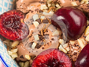 Chocolate ice cream with sprinkles, nuts and fresh cherries, closeup