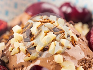 Chocolate ice cream with sprinkles, nuts and fresh cherries, closeup