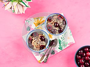 Chocolate ice cream with sprinkles, nuts and fresh cherries on pink