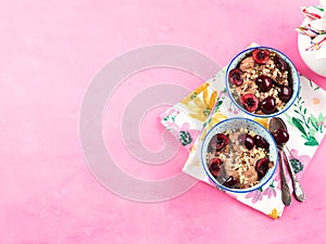 Chocolate ice cream with sprinkles, nuts and fresh cherries on pink