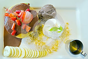 Chocolate ice-cream with strawberry, whip cream served with banana, chocolate filled crepe and natural honey