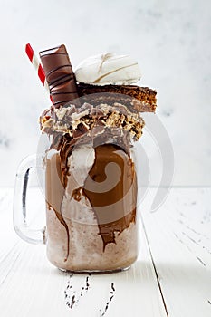 Chocolate indulgent exreme milkshake with brownie cake, marshmallow and sweets. Crazy freakshake food trend.
