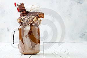 Chocolate indulgent extreme milkshake with brownie cake, marshmallow and sweets. Crazy freakshake food trend.