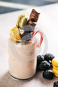 Chocolate indulgent extreme milkshake with macaroons, berry and sweets. Crazy freakshake food trend. Copy space