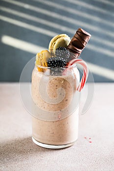 Chocolate indulgent extreme milkshake with macaroons, berry and sweets. Crazy freakshake food trend. Copy space