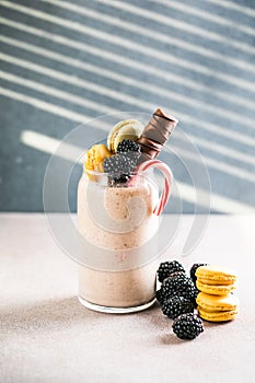 Chocolate indulgent extreme milkshake with macaroons, berry and sweets. Crazy freakshake food trend. Copy space