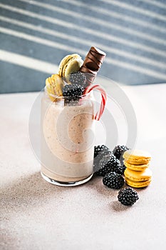 Chocolate indulgent extreme milkshake with macaroons, berry and sweets. Crazy freakshake food trend. Copy space