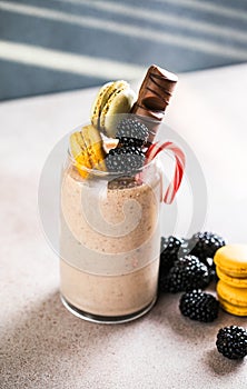 Chocolate indulgent extreme milkshake with macaroons, berry and sweets. Crazy freakshake food trend. Copy space