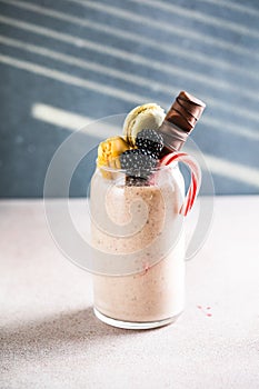 Chocolate indulgent extreme milkshake with macaroons, berry and sweets. Crazy freakshake food trend. Copy space