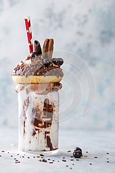 Chocolate indulgent frosting exreme milkshake with donut  and sweets. Crazy freakshake food trend. Copy space