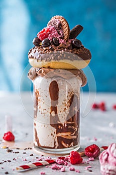 Chocolate indulgent frosting exreme milkshake with donut  and sweets. Crazy freakshake food trend. Copy space