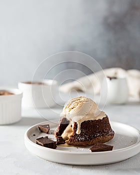Chocolate lava cake with liquid centre and ice cream scoop on white background. Restaurant menu, recipe. Side view, copy space