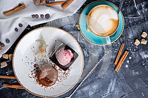 Chocolate lava cake Molten with ice cream on plate and cappuccino. Balls of ice cream in cup . Dark black background.