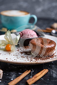 Chocolate lava cake Molten with ice cream on plate and cappuccino. Balls of ice cream in cup . Dark black background.