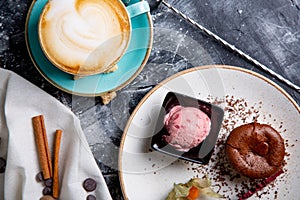 Chocolate lava cake Molten with ice cream on plate and cappuccino. Balls of ice cream in cup . Dark black background.