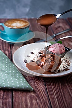 Chocolate lava cake Molten with ice cream on plate and cappuccino. Balls of ice cream in cup . Dark black background.