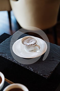 Chocolate lava cake topping with icing sugar inside white ceramic cup