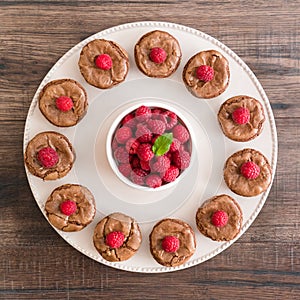 Chocolate lava cakes with fresh rspberries and mint leaf arranged in a circle on the porcelan plate