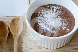 Chocolate lava in white cup with powder and wood spoon