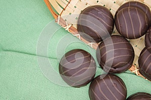 Chocolate macaroons in a basket on green background