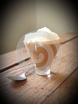 Chocolate Macchiato in small glass with spoon on wooden distressed table