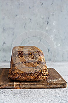 Chocolate marbled cake biscuit Zebra with chocolate icing on a wooden board on a gray background.