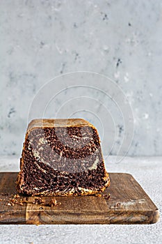 Chocolate marbled cake biscuit Zebra with chocolate icing on a wooden board on a gray background.