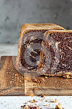 Chocolate marbled cake biscuit Zebra with chocolate icing on a wooden board on a gray background.