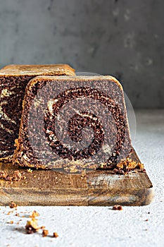 Chocolate marbled cake biscuit Zebra with chocolate icing on a wooden board on a gray background.