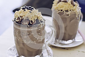 Chocolate Milkshake with chocolate cereals, cheese, and Choco chips in the big clear glass cup. Selective focus close-up on top of