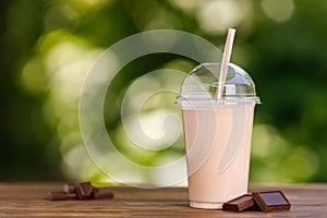 chocolate milkshake in disposable plastic glass on wooden table