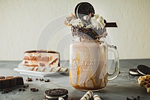 Chocolate milkshake with dripping sauce, cream, cocoa cookies and cake