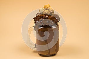 Chocolate milkshake with whipped cream, cookies, waffles, served in glass mason jar.