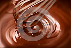 Chocolate. Mixing melted dark chocolate with a whisk. Closeup of liquid hot chocolate swirl