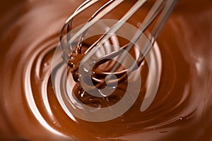 Chocolate. Mixing melted dark chocolate with a whisk. Closeup of liquid hot chocolate swirl