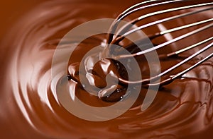 Chocolate. Mixing melted dark chocolate with a whisk. Closeup of liquid hot chocolate swirl