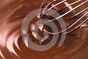 Chocolate. Mixing melted dark chocolate with a whisk. Closeup of liquid hot chocolate swirl