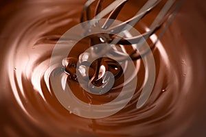 Chocolate. Mixing melted dark chocolate with a whisk. Closeup of liquid hot chocolate swirl