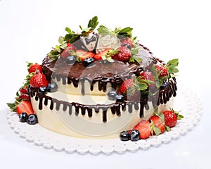 Chocolate mousse cake decorated with strawberries and blueberries on a white background
