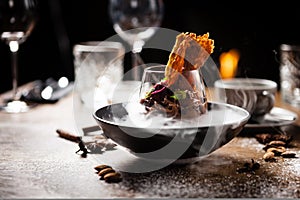 Chocolate mousse with coffee liquor, cherry, kama biscuit in liquid ice smoke in a bowl. Delicious healthy food closeup