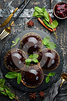 Chocolate-mousse dessert `Opera` on a black plate with mint. Top view. Rustic style