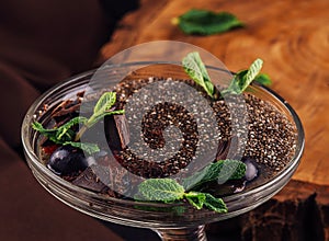 Chocolate mousse dessert with prunes and mint leaves in portion glasses