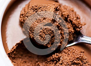 Chocolate Mousse in White Cup Bowl. Spoonful Visible Spongy Texture with Pores. Vibrant Rich Brown Color. Macro