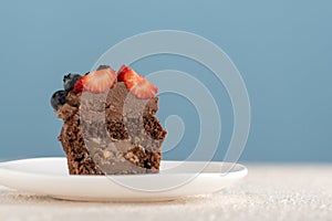 Chocolate muffin with caramel filling and berries. Chocolate cupcake with dark chocolate icing on blue background